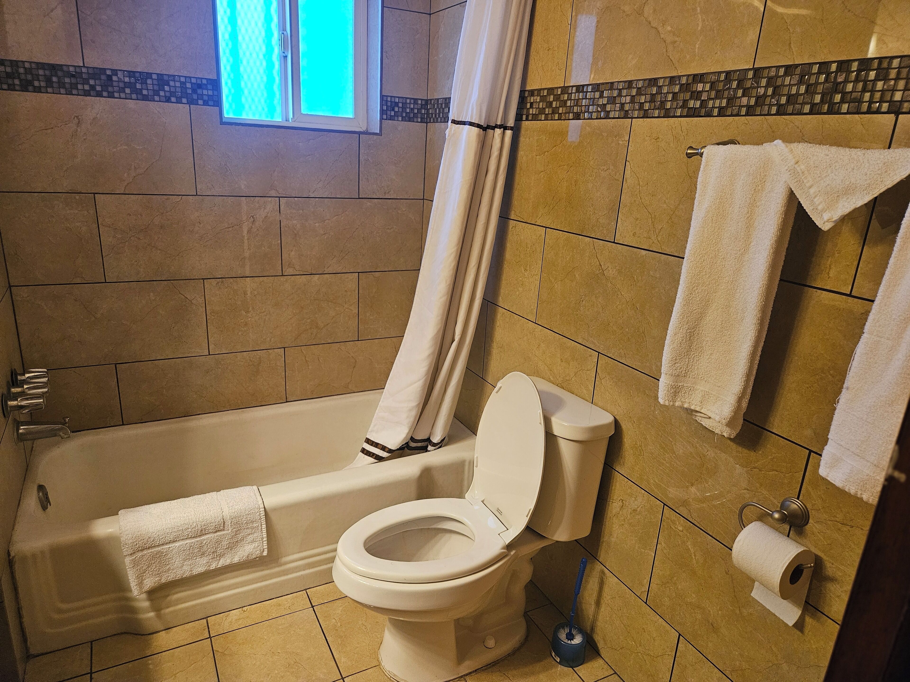 A bathroom with a bathtub, toilet, and shower curtain.