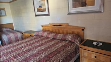 Un dormitorio con dos camas, cabeceros de madera, una mesita de noche y un cuadro enmarcado en la pared.