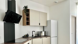 Een moderne keuken met een ingebouwde magnetron, oven en koelkast. Er is een houten aanrecht en een spoelbak met een kraan.
