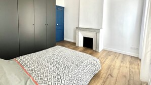 Een slaapkamer met een bed, een kledingkast, een blauwe deur en een open haard.