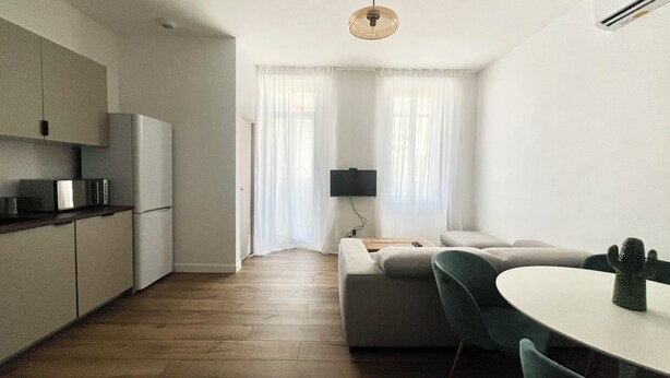 Een moderne keuken met een magnetron, koelkast en houten vloer.
