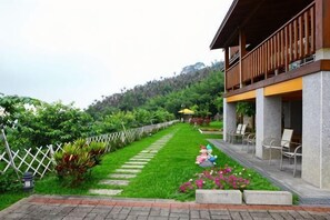 Un hotel con balcón, un sendero de jardín y mobiliario exterior.
