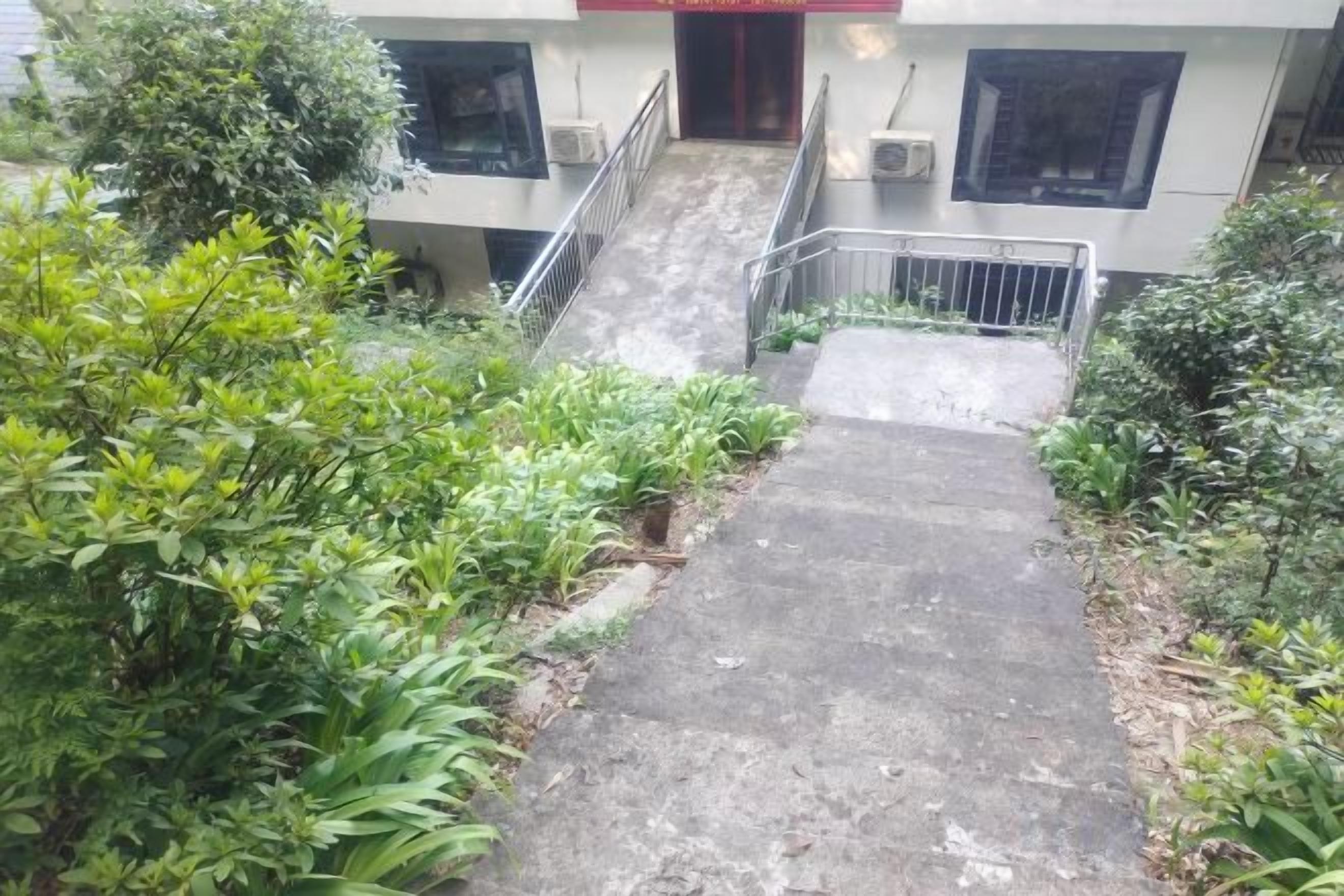 A concrete pathway leading to a building entrance with a metal railing.