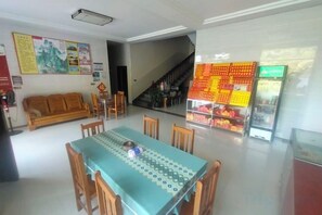 A dining area with a table and chairs, a sofa, a staircase, and a fruit display. - Hengyang Nanyueshan Xiangyuan Manor (Hengyang)