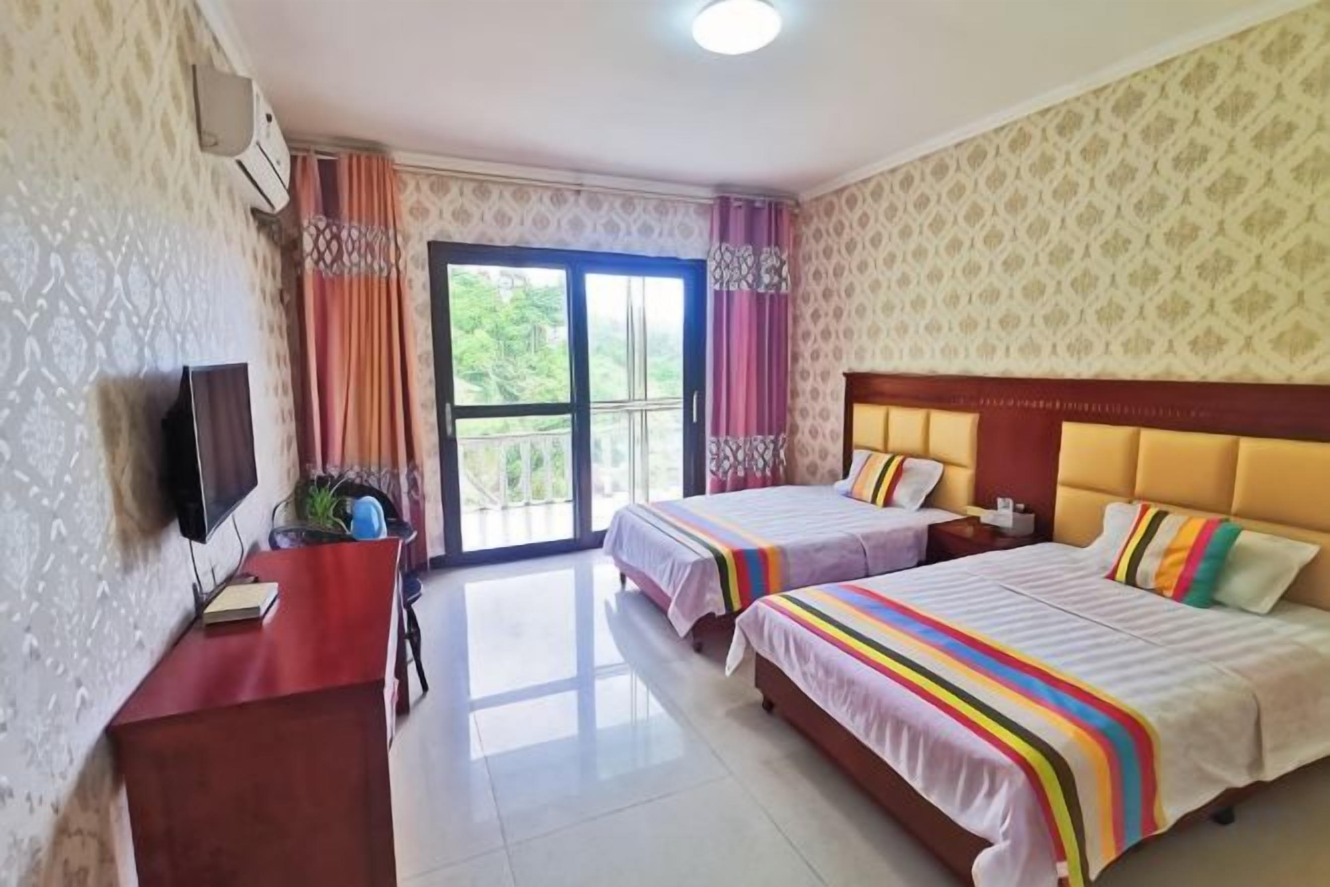 Habitación de hotel con dos camas, televisión, escritorio y balcón.