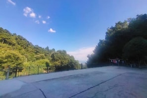 A paved area with a metal fence, surrounded by dense green trees and a clear sky. - Hengyang Nanyueshan Xiangyuan Manor (Hengyang)
