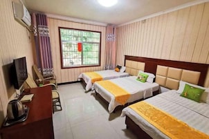 Habitación de hotel con dos camas, un escritorio, un televisor y una ventana con cortinas.
