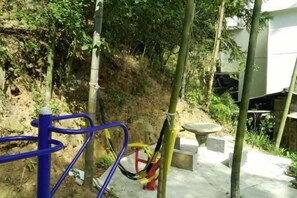 An outdoor area with exercise equipment, a concrete path, and a hillside. - Hengyang Nanyueshan Xiangyuan Manor (Hengyang)