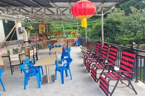 Un espace extérieur aménagé pour les repas, avec des tables et des chaises, un barbecue et une lanterne rouge.
