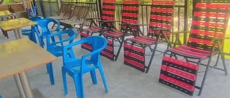 An outdoor seating area with blue chairs and red and black cushioned chairs.