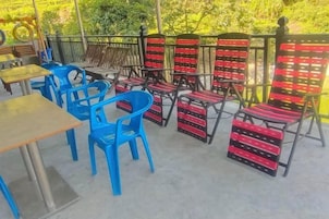 Un área de estar al aire libre con sillas azules y sillones con cojines rojo y negro.