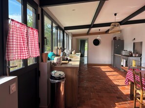 Une cuisine dotée d’une grande fenêtre, un coin repas avec une table et des chaises, et une vue sur l’extérieur.