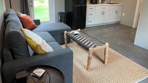 A modern living room with a grey sectional sofa, a small wooden bench, and a coffee station. - Cozy cottage in charming downtown Mount Vernon. (Mount Vernon)
