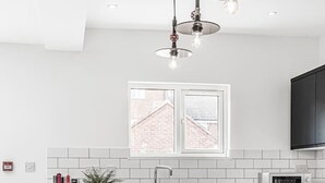Une cuisine moderne dotée d’un îlot central, de tabourets de bar, d’un four à micro-ondes et d’une fenêtre donnant sur un bâtiment en briques.