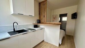 A compact kitchen with white cabinets, a black sink, and a wooden countertop.
