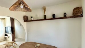 Ein Essbereich mit einem Holztisch und einer Bank, einer hängenden Leuchte und einem Regal mit Dekoration.