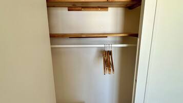 A small, narrow closet with wooden shelves and a hanging rod.
