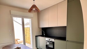 Eine kleine Küche mit Esstisch und Bank, einem eingebauten Backofen und einer Schiebetür zu einem Außenbereich.