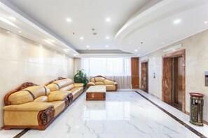 A spacious lobby with a marble floor, leather sofas, a coffee table, and a plant. - Yang Quan Hotel (Yangquan)
