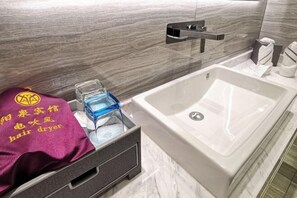 A bathroom with a white sink, a towel rack, and a hair dryer in a drawer. - Yang Quan Hotel (Yangquan)