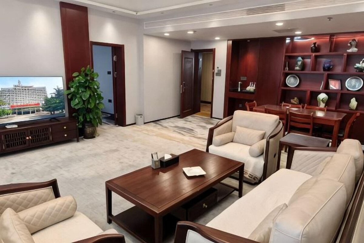 A hotel lobby with a sofa set, a coffee table, a television, and a bookshelf.