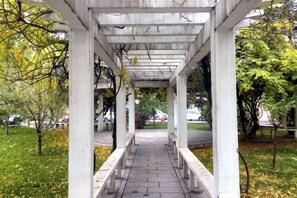 A covered walkway with benches, surrounded by trees and grass. - Yang Quan Hotel (Yangquan)