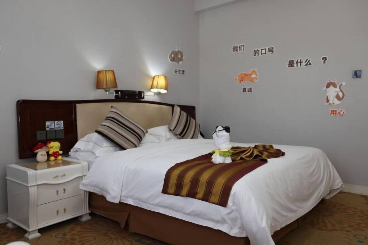 A hotel room with a bed, a nightstand, a lamp, and wall decals.