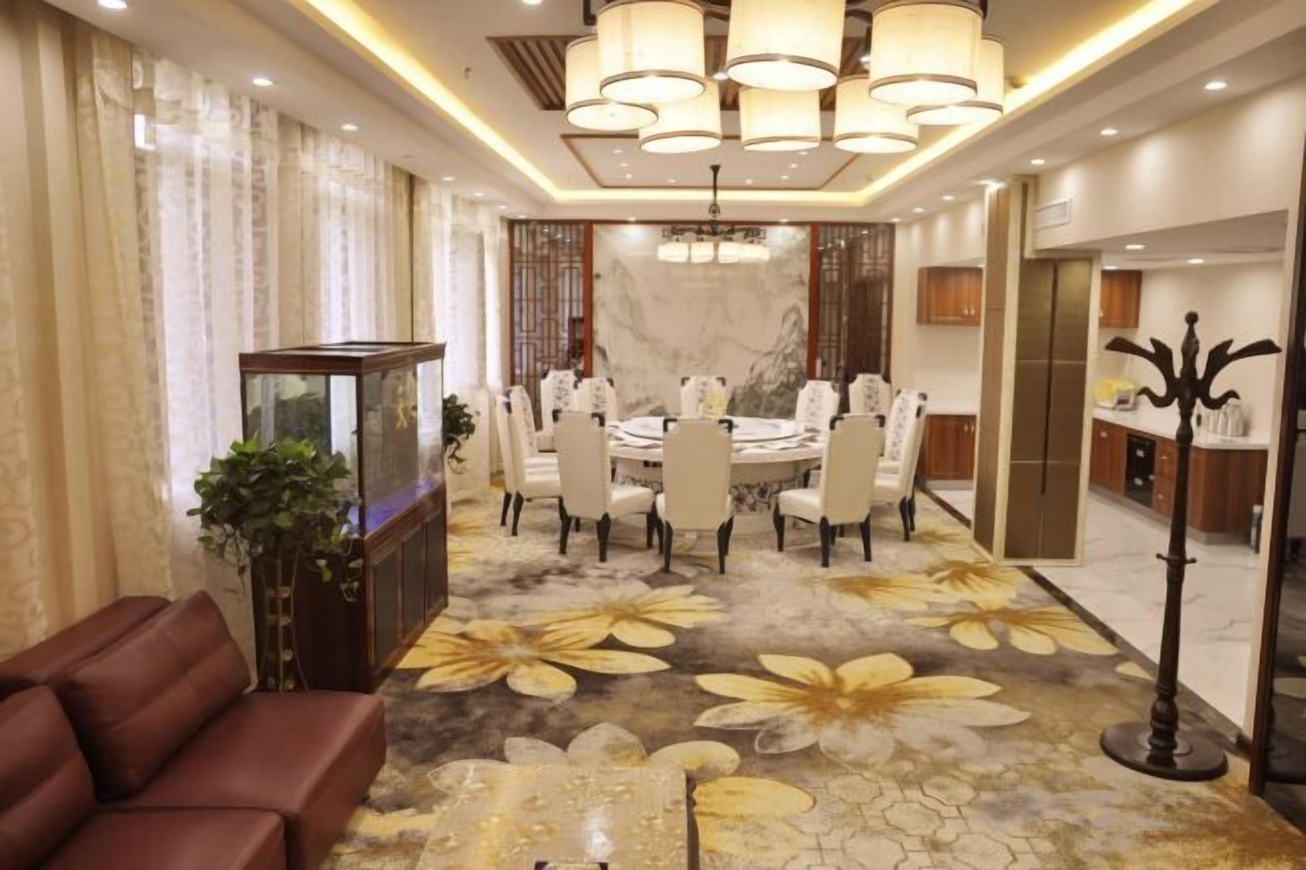 A hotel dining area with a round table, chairs, and a chandelier.