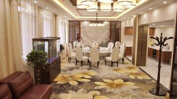 A hotel dining area with a round table, chairs, and a chandelier.