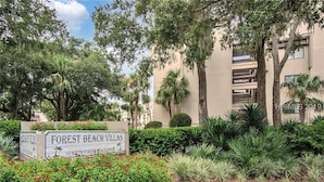 Une enseigne indiquant l’emplacement de Forest Beach Villas, avec un jardin luxuriant et des palmiers.