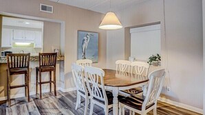 Un espace repas avec une table ronde, des chaises blanches et un luminaire suspendu.