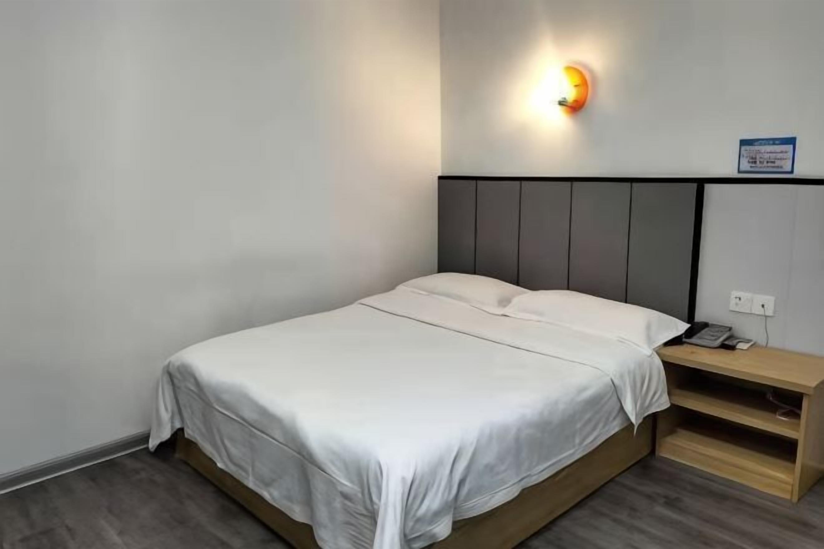 Un letto singolo con testiera, un comodino e un lampadario a parete.