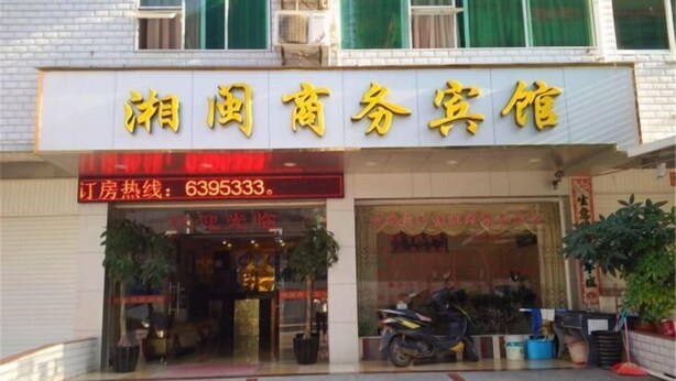 Fachada de un comercio con un cartel que dice 'Shengguang Business Hotel' y el número de teléfono '6395333' para consultas.