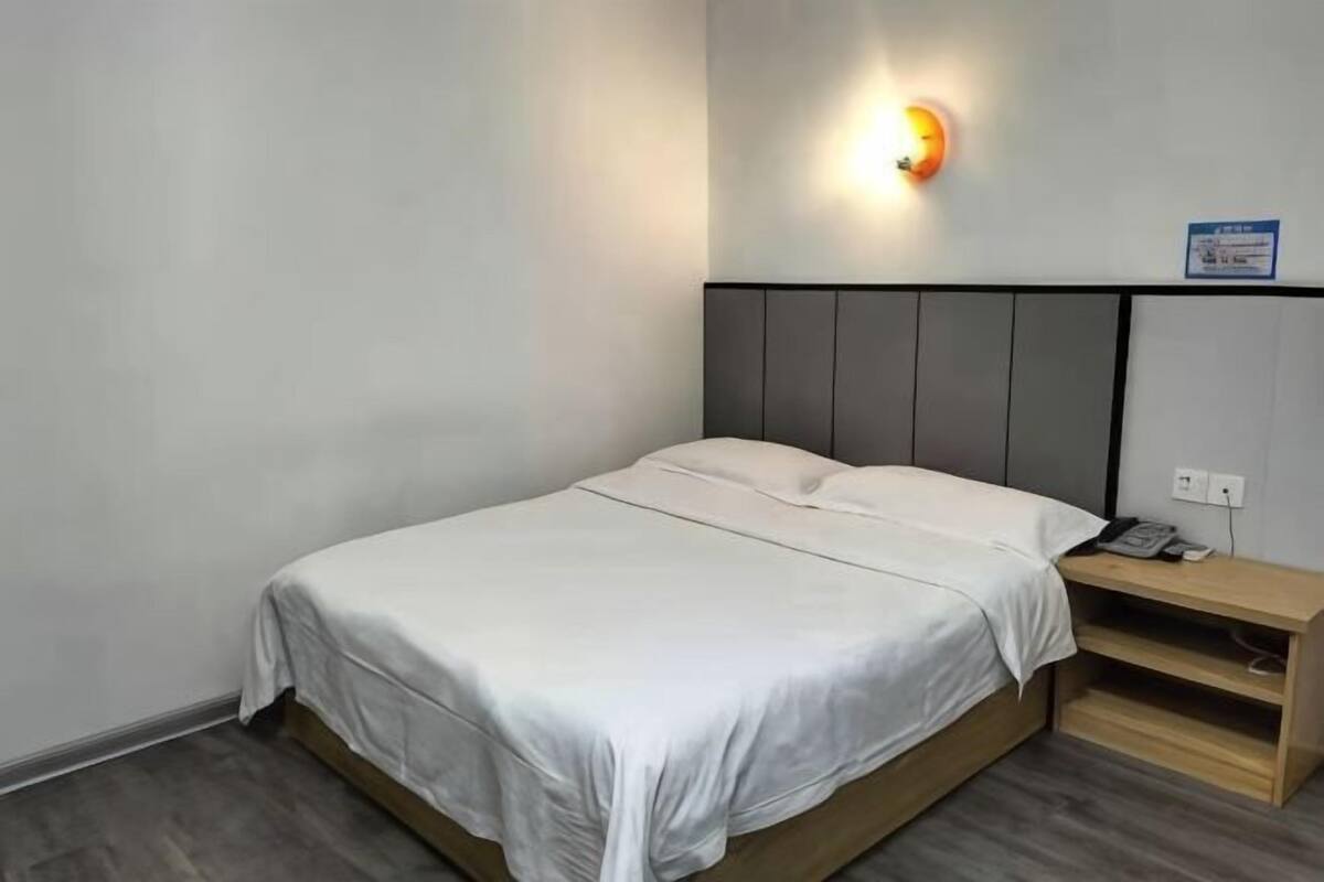 Ein Einzelbett mit Holzrahmen, ein Nachttisch und eine Wandleuchte.