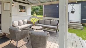 A covered outdoor seating area with wicker furniture and a white door.