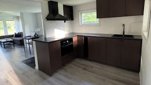 A modern kitchen with dark cabinetry, a built-in oven, and a window providing natural light.