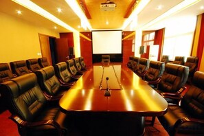 A conference room with a long table and multiple chairs, a projector screen, and a large window. - Xiangbala Hotel (Muli)