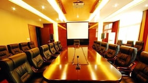 A conference room with a long table and leather chairs, a projector screen, and a large window. - Xiangbala Hotel (Muli)