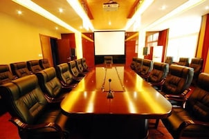 A conference room with a long table and leather chairs, a projector screen, and a large window.