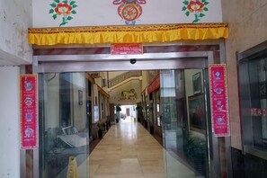 A corridor with glass doors, a yellow decorative trim, and red banners on the walls. - Xiangbala Hotel (Muli)