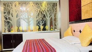 A hotel room with a bed, a striped throw blanket, a decorative window with a tree design, and a red and gold headboard. - Xiangbala Hotel (Muli)