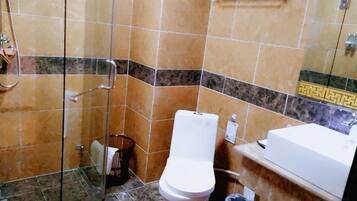 A bathroom with a glass-enclosed shower, a toilet, and a sink.
