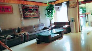 A spacious living room with a sofa set, a coffee table, and a large window providing natural light.
