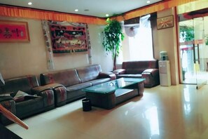 A spacious living room with a sofa, armchairs, a coffee table, and a large window. - Xiangbala Hotel (Muli)