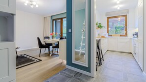 A modern kitchen with white cabinets, a window with a view, and a dining area with a table and chairs. - Grzybowska 85a (Warsaw)