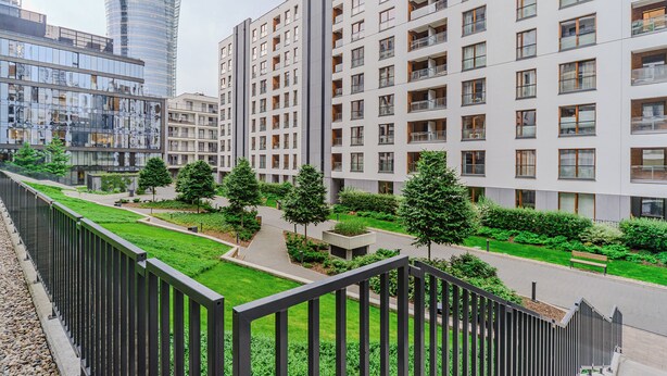 A modern residential building with multiple balconies, a central courtyard with greenery, and a pedestrian pathway. - Grzybowska 85a (Warsaw)