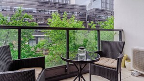 A balcony with wicker furniture, a glass table, and a view of a cityscape. - Grzybowska 85a (Warsaw)