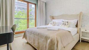 A bedroom with a bed, a desk, and a window with curtains. - Grzybowska 85a (Warsaw)