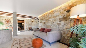 Una sala de estar moderna con pared de piedra, sofá gris, lámpara de pie de madera y alfombra estampada.