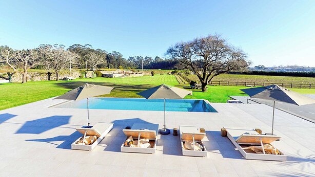 Zona junto a la piscina con sillones de descanso y una vista despejada del paisaje circundante.